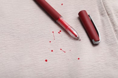 Photo of Pen and stains of red ink on shirt, closeup. Space for text