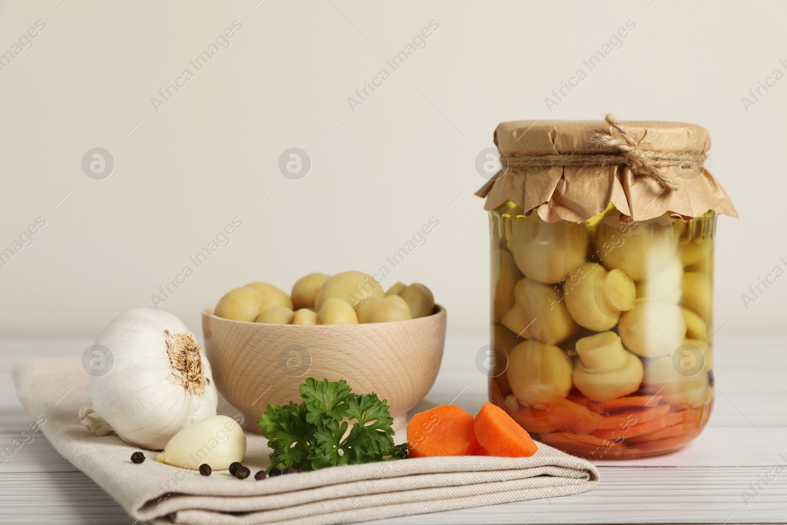 Photo of Tasty pickled mushrooms and spices on white wooden table