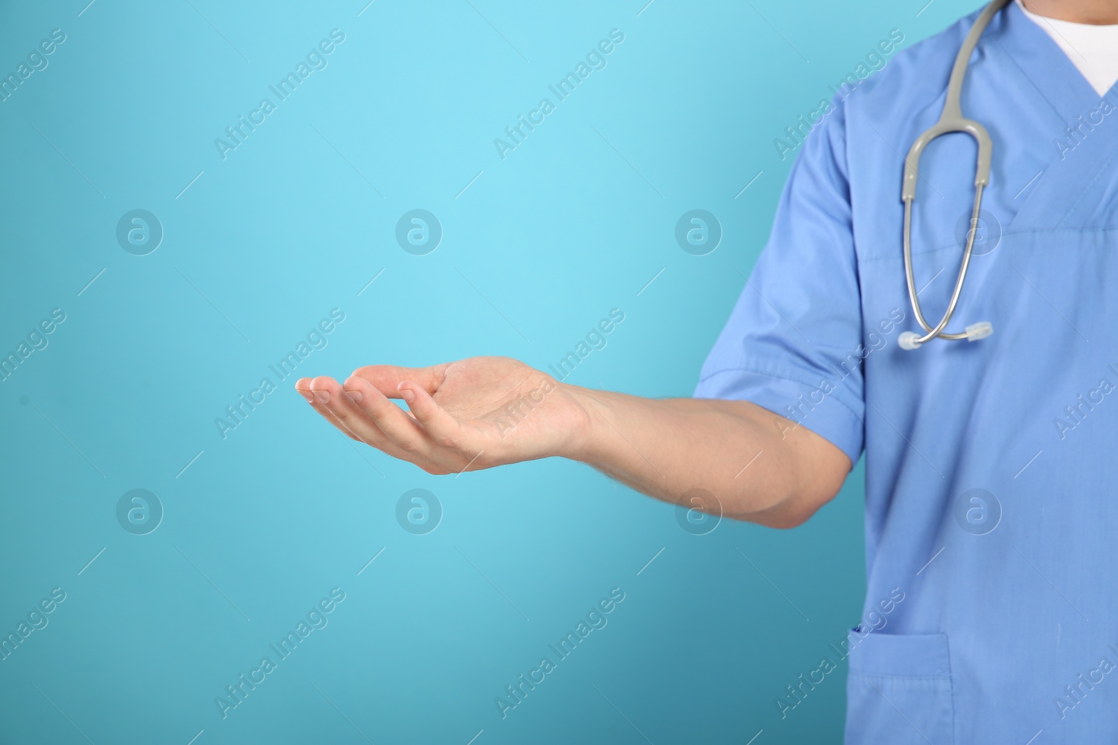 Photo of Doctor with stethoscope holding something on light blue background, closeup. Space for text