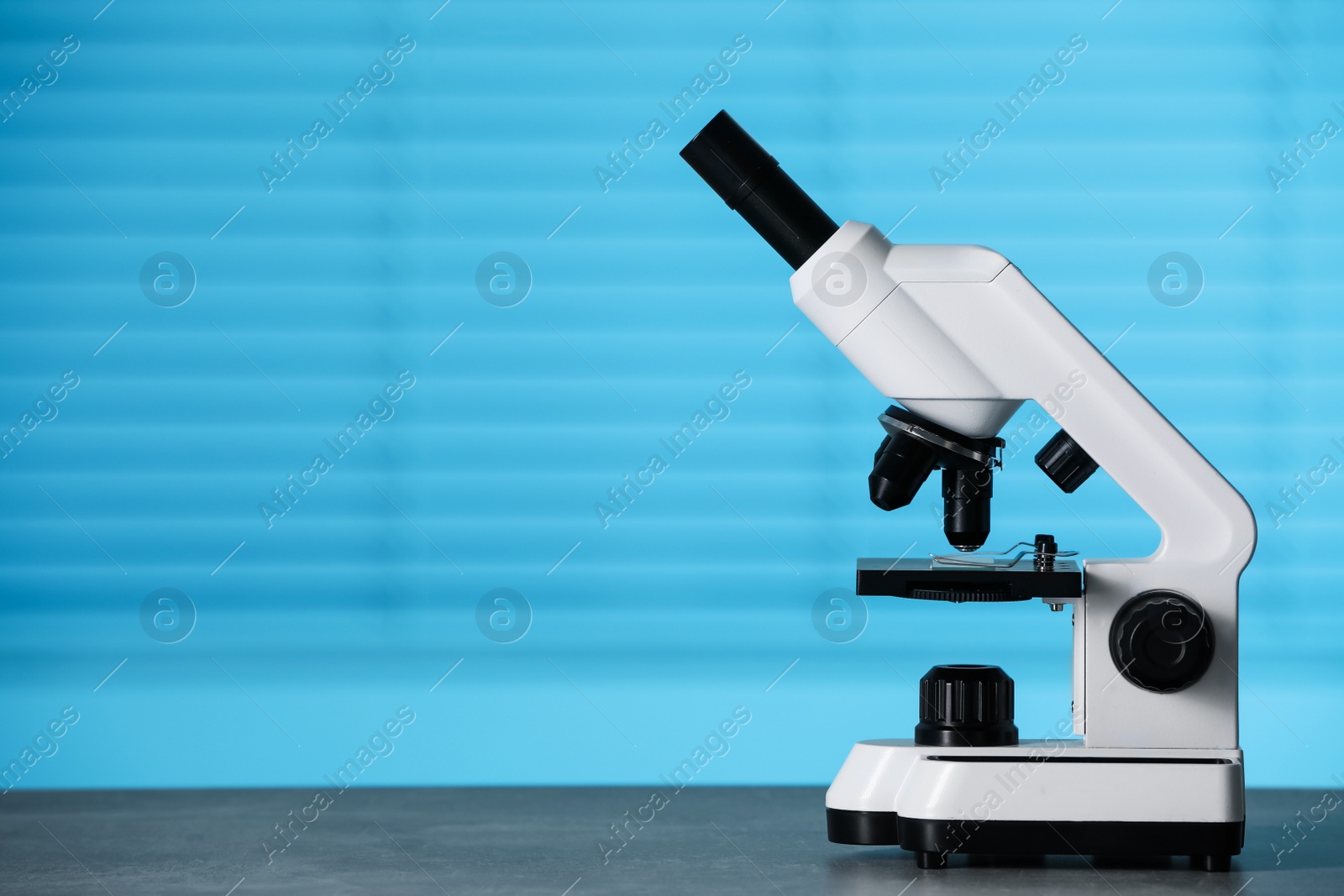 Photo of Modern medical microscope on grey table indoors, space for text