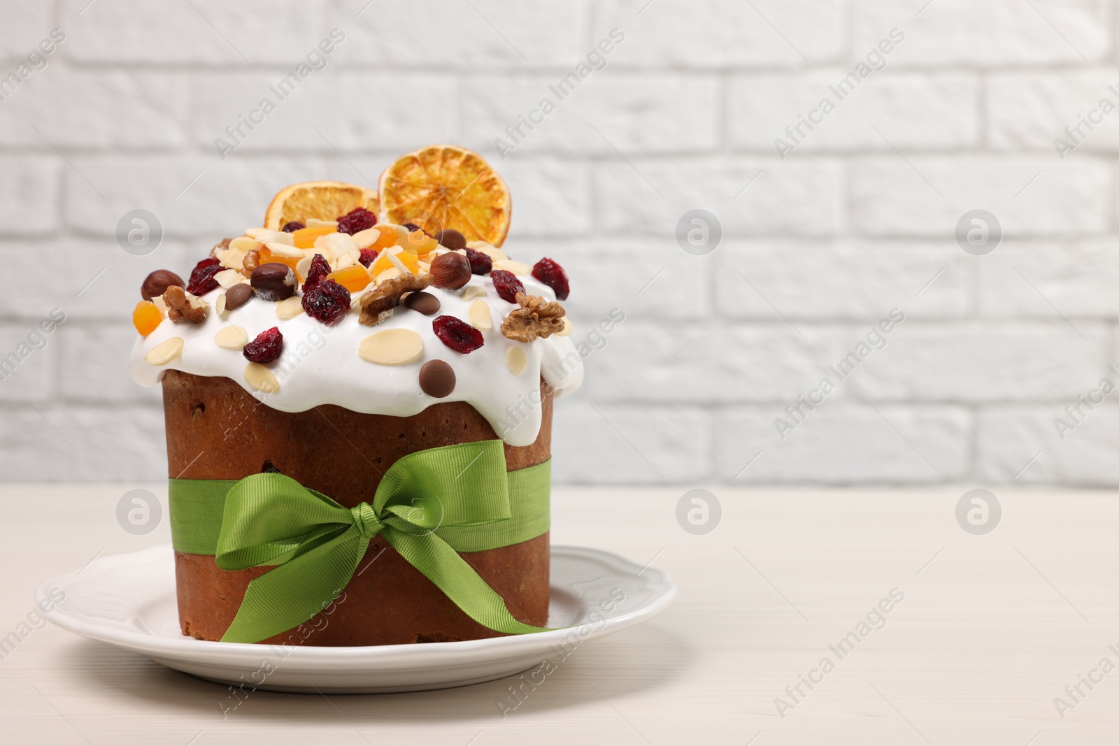 Photo of Tasty Easter cake with dried fruits and nuts on white wooden table. Space for text