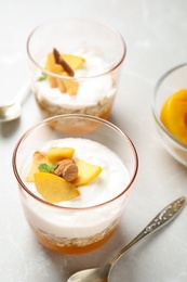 Photo of Tasty peach dessert with yogurt and granola served on light table