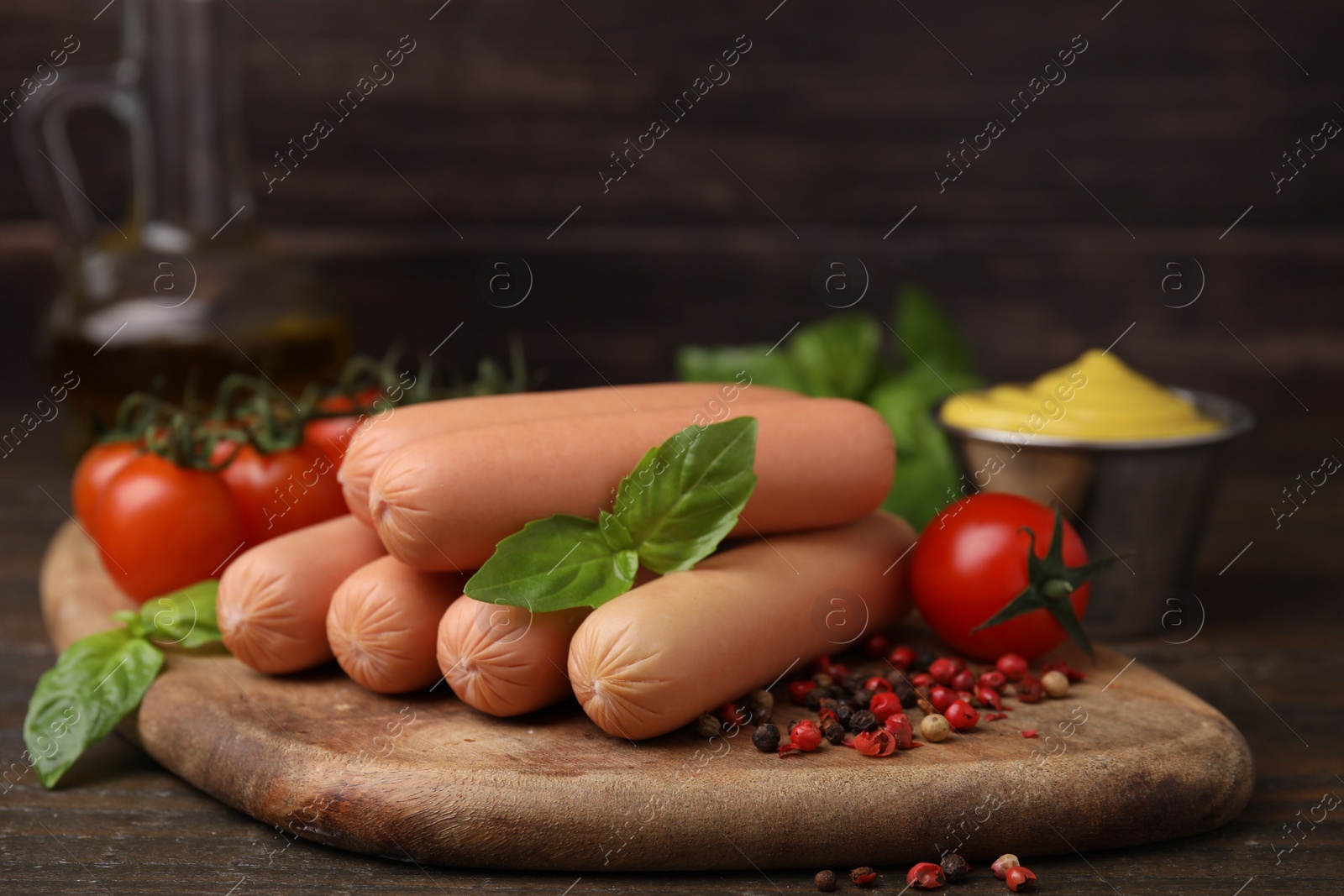 Photo of Delicious boiled sausages, tomatoes, basil and peppercorns on wooden table, closeup