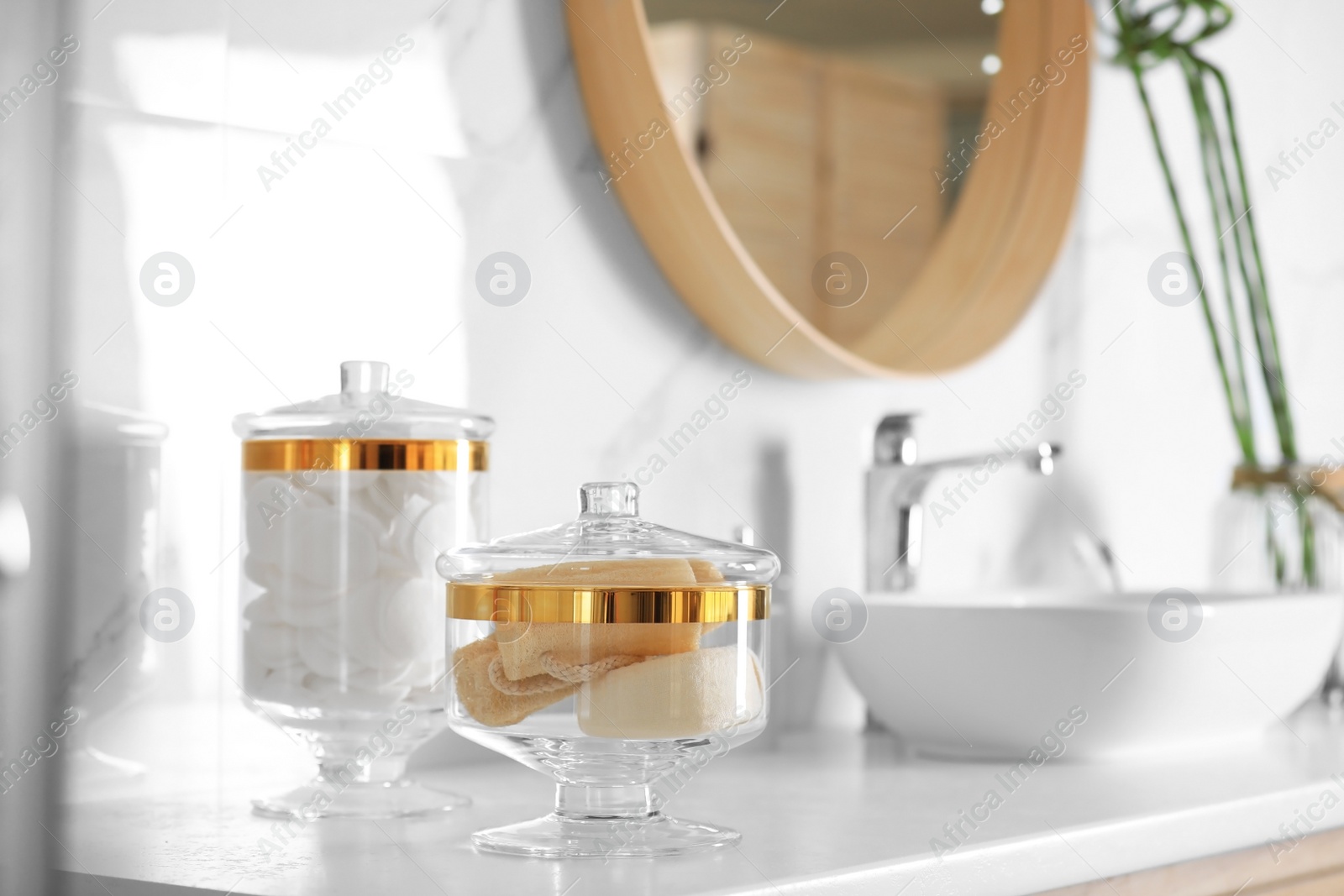 Photo of Jars with cotton pads and loofah sponges on countertop in bathroom