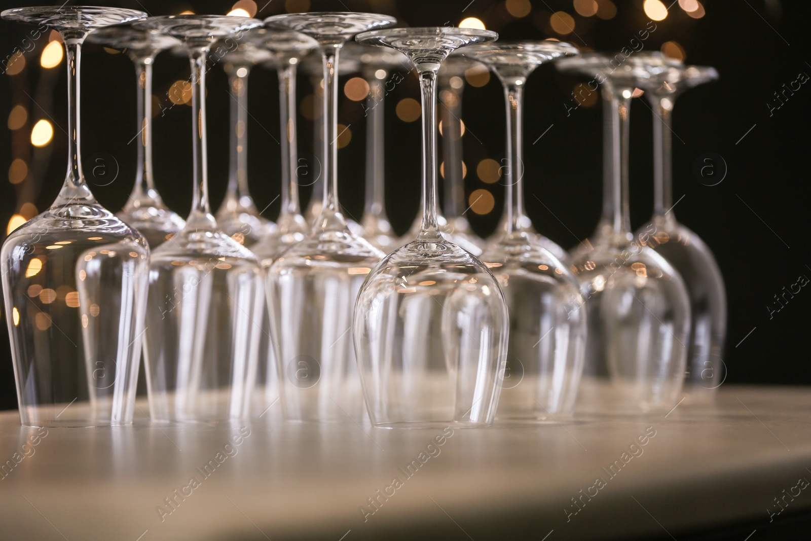 Photo of Empty glasses on grey table against blurred lights