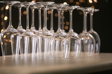 Photo of Empty glasses on grey table against blurred lights