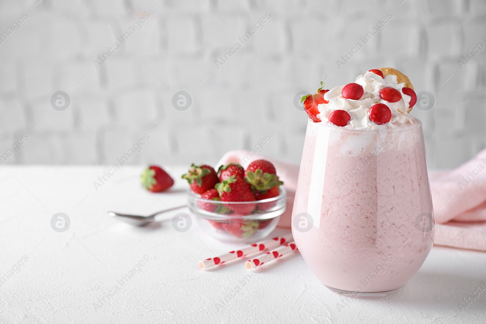 Photo of Tasty strawberry milk shake in glass on white table. Space for text