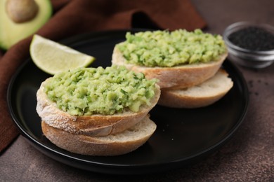 Photo of Delicious sandwiches with guacamole on black plate, closeup