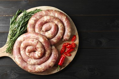 Raw homemade sausage, chili pepper and rosemary on dark wooden table, top view. Space for text