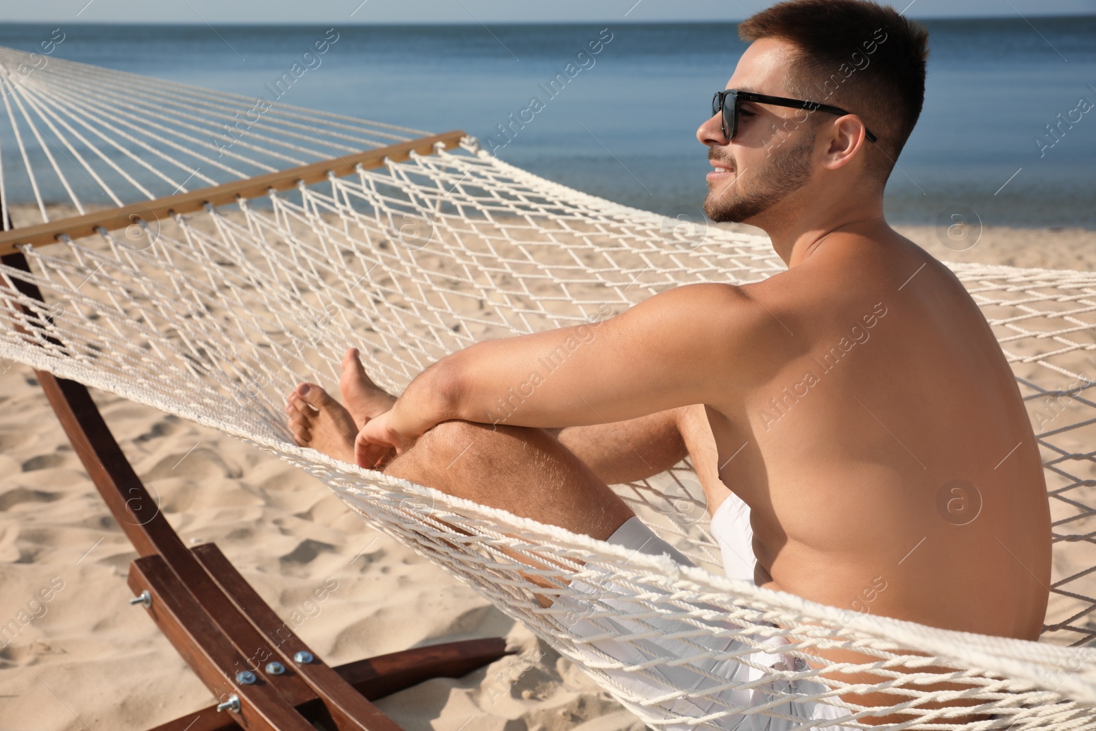 Photo of Young man relaxing in hammock on beach