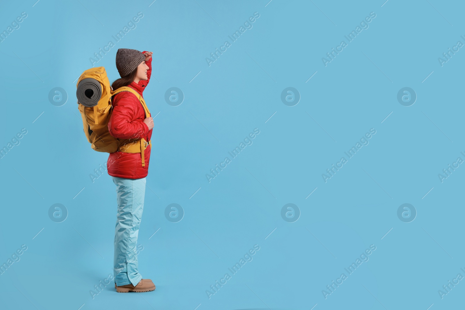 Photo of Young woman with backpack on light blue background, space for text. Active tourism