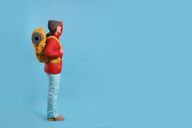 Photo of Young woman with backpack on light blue background, space for text. Active tourism