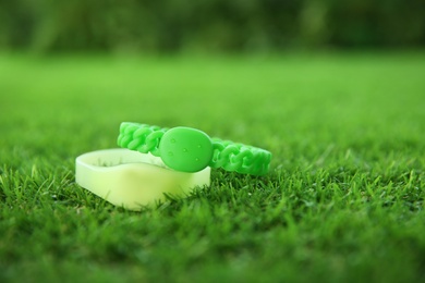Photo of Insect repellent wrist bands on green grass. Space for text