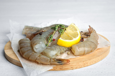 Photo of Fresh raw shrimps with lemon and thyme on white wooden table, closeup