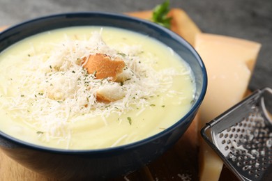 Delicious cream soup with parmesan cheese and croutons in bowl on table, closeup