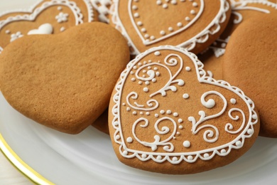 Tasty heart shaped gingerbread cookies in plate, closeup