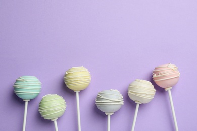 Photo of Sweet cake pops on purple background, flat lay. Space for text