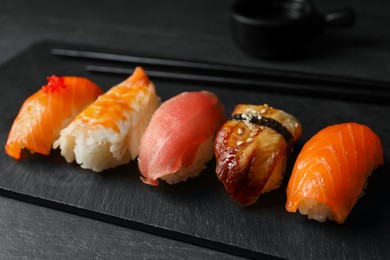 Photo of Plate with delicious nigiri sushi on black table