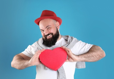 Emotional man with heart shaped box on color background