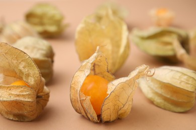 Ripe physalis fruits with calyxes on beige background, closeup