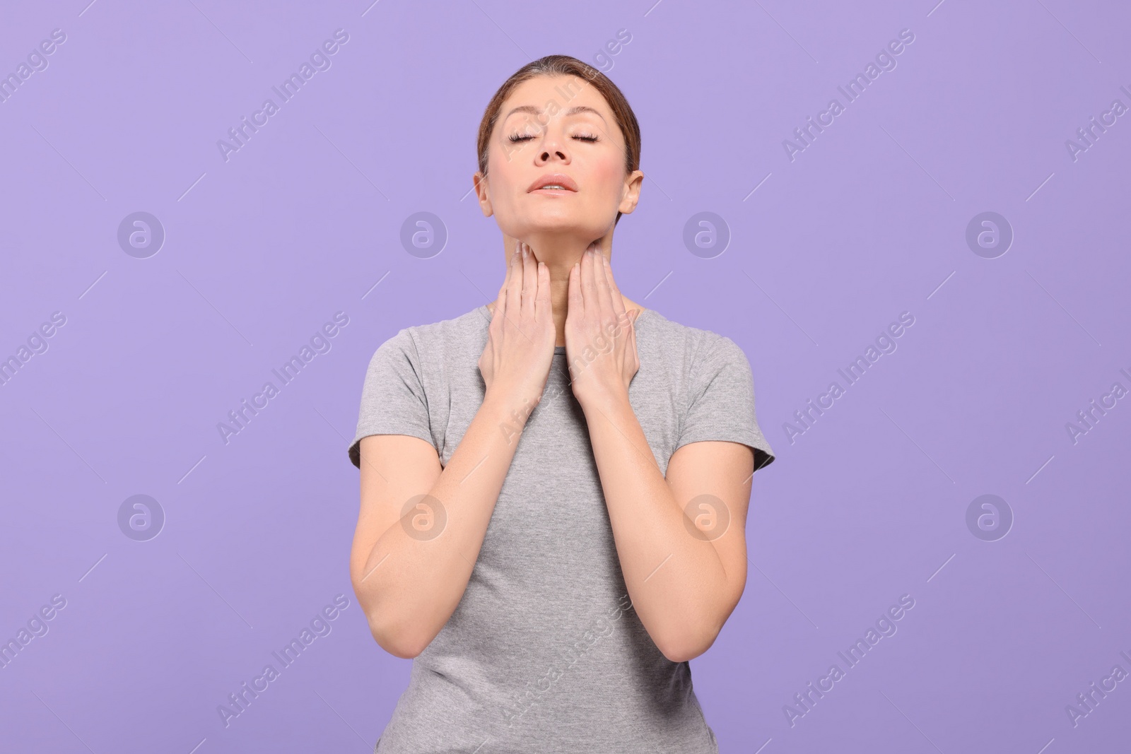 Photo of Woman suffering from sore throat on violet background