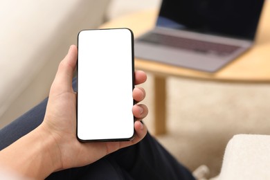 Man using smartphone with blank screen indoors, closeup. Mockup for design