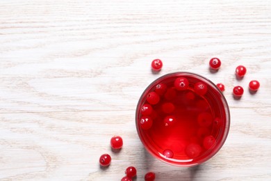 Photo of Tasty cranberry juice in glass and fresh berries on white wooden table, flat lay. Space for text