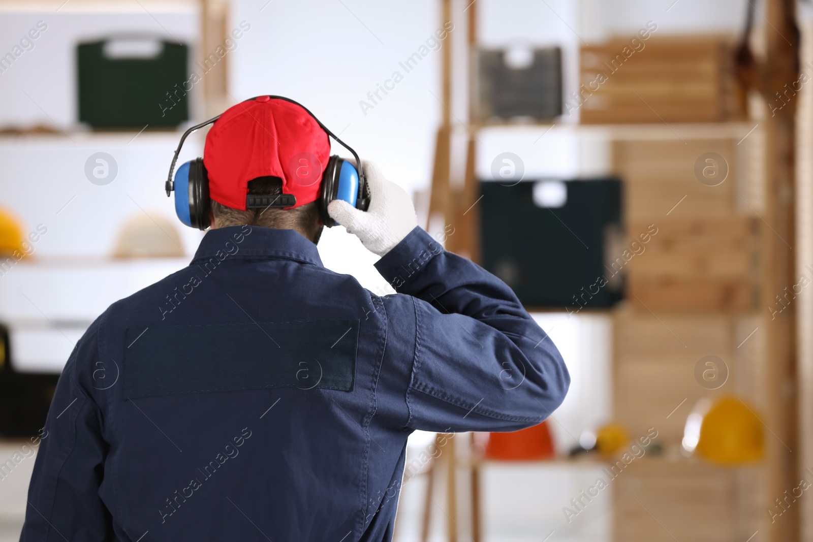 Photo of Worker wearing safety headphones indoors, back view. Hearing protection device