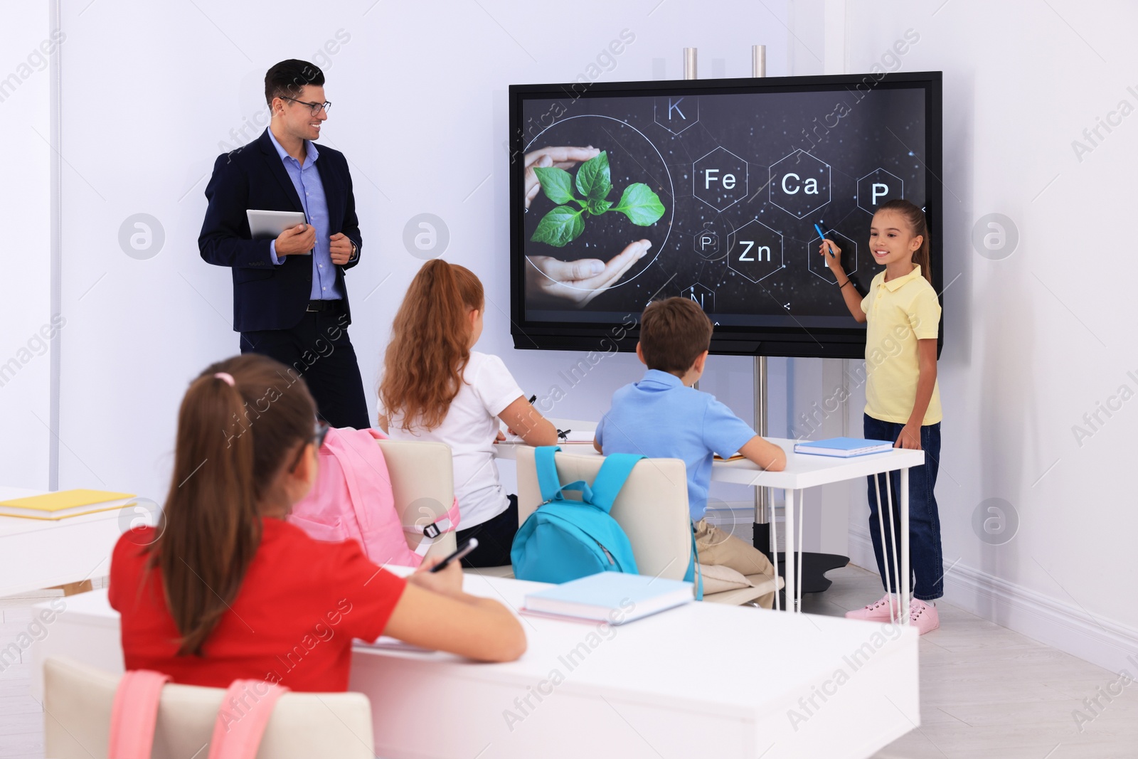 Photo of Teacher and pupil using interactive board in classroom during lesson