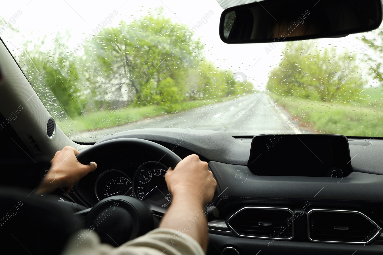 Photo of Man driving car on rainy day, closeup of hands