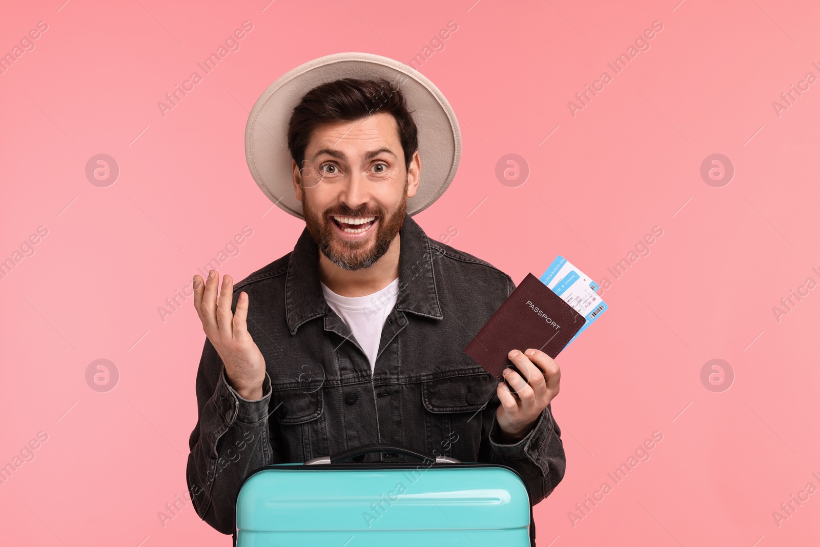 Photo of Smiling man with passport, tickets and suitcase on pink background