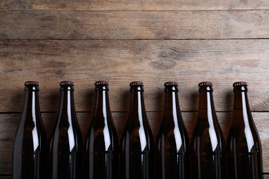 Photo of Bottles of beer on wooden table, flat lay. Space for text
