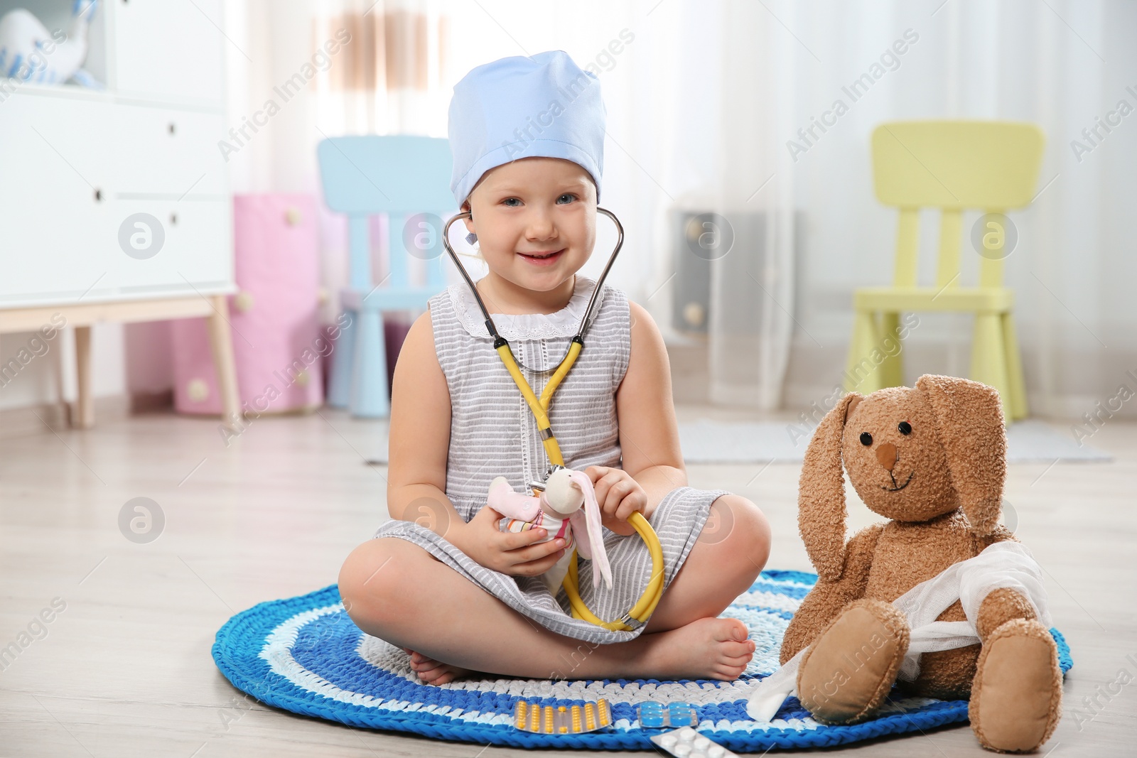 Photo of Cute child imagining herself as doctor while playing with stethoscope and toy bunny at home