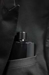 Photo of Luxury men's perfume in breast pocket of black jacket, top view