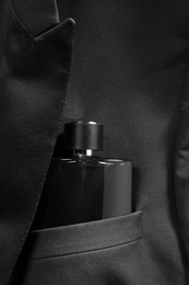 Luxury men's perfume in breast pocket of black jacket, top view