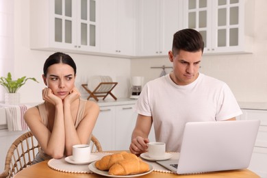 Photo of Internet addiction. Man with laptop ignoring his girlfriend in kitchen