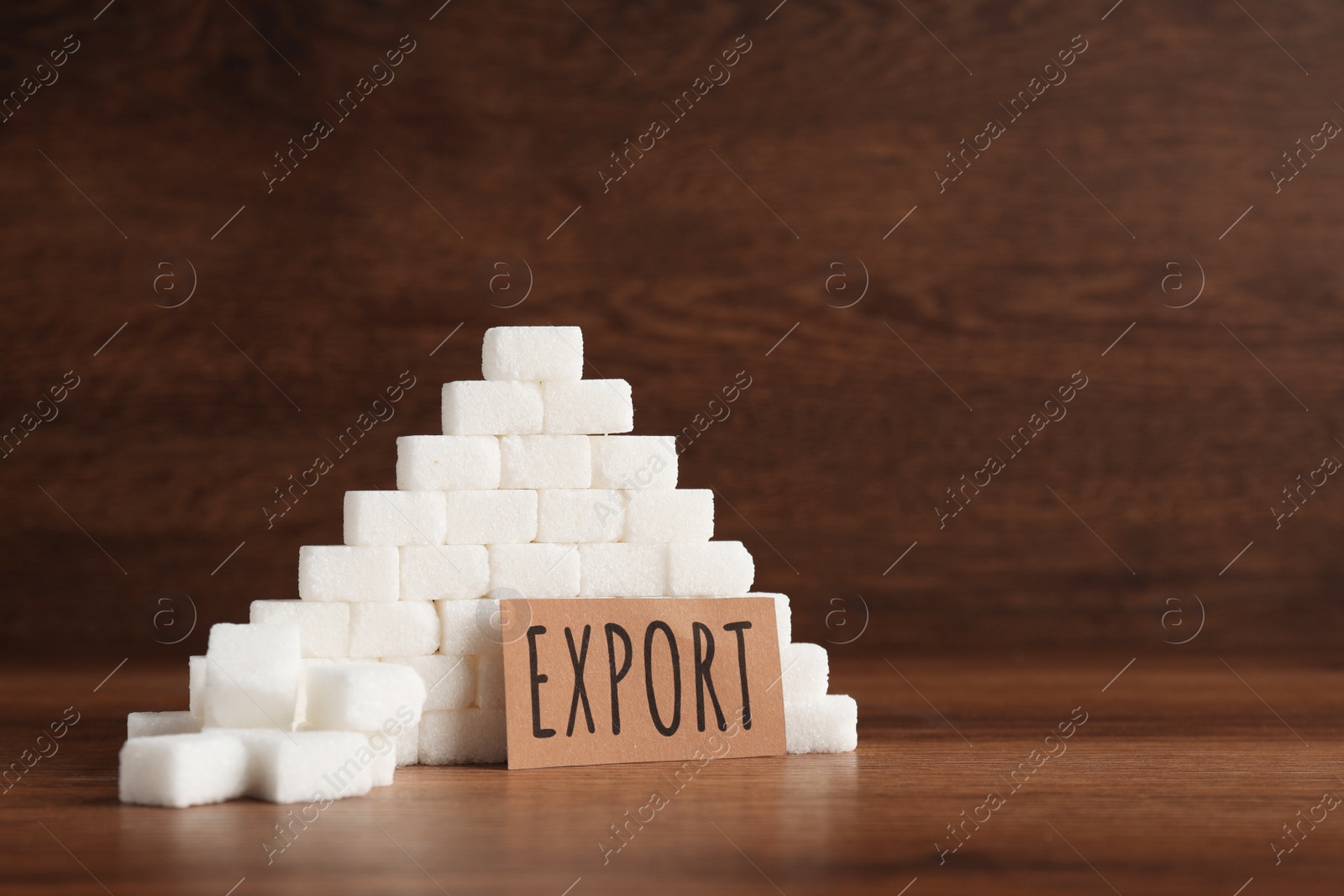 Photo of Card with word Export near pyramid of sugar cubes on wooden table, space for text