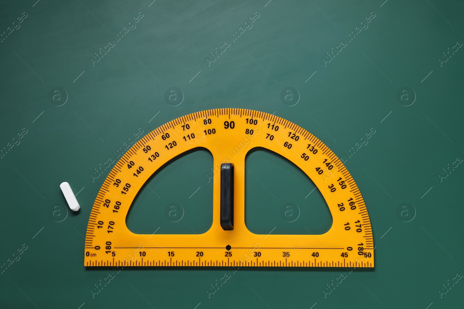 Photo of Yellow protractor and chalk on green chalkboard, flat lay. Space for text