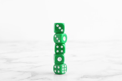 Photo of Many stacked green dices on white marble table