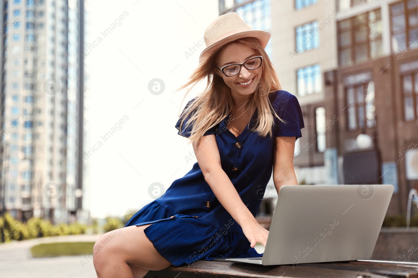 Photo of Beautiful woman with laptop on city street