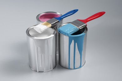 Photo of Cans of paints and brushes on light blue background