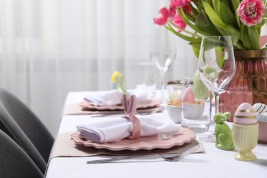 Photo of Festive table setting with napkin ring in shape of bunny ears. Easter celebration