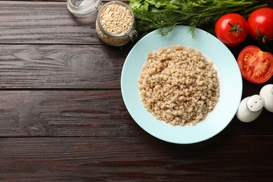 Photo of Delicious pearl barley served on wooden table, flat lay. Space for text