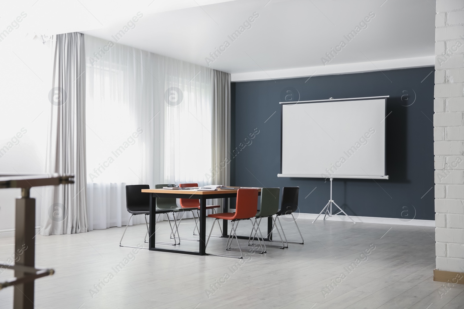 Photo of Modern meeting room interior with large table and projection screen