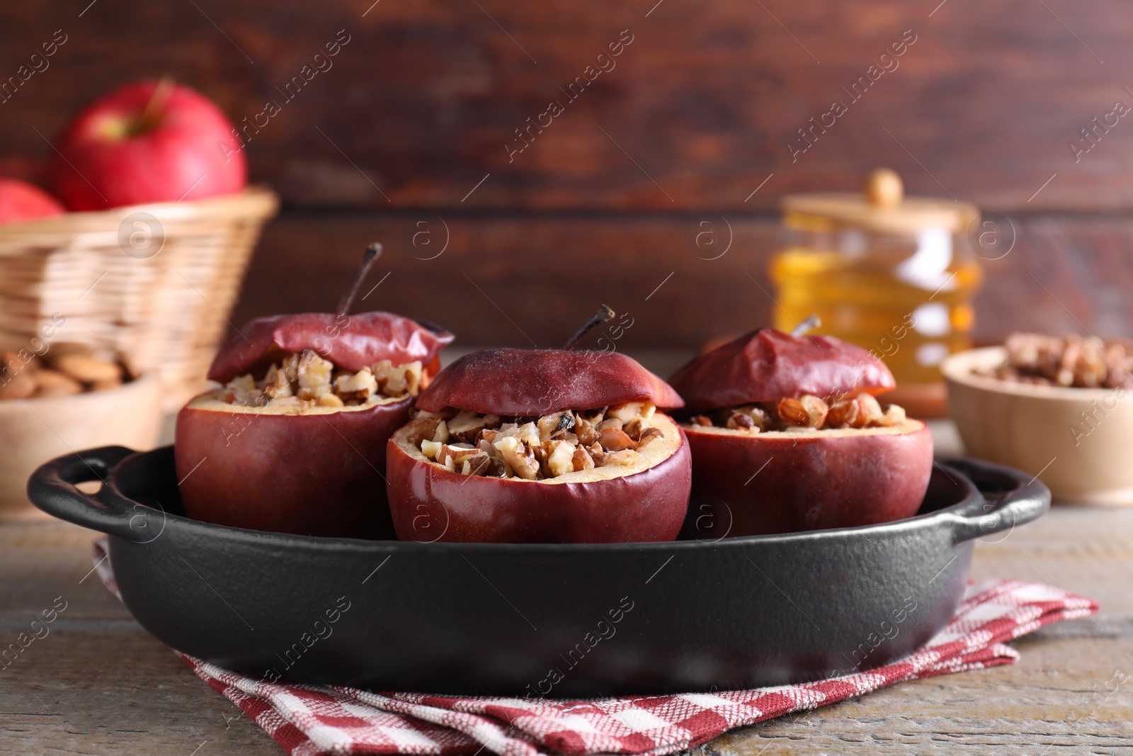 Photo of Tasty baked apples with nuts in baking dish on wooden table, closeup