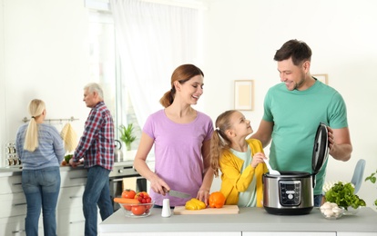 Happy family preparing food with modern multi cooker in kitchen