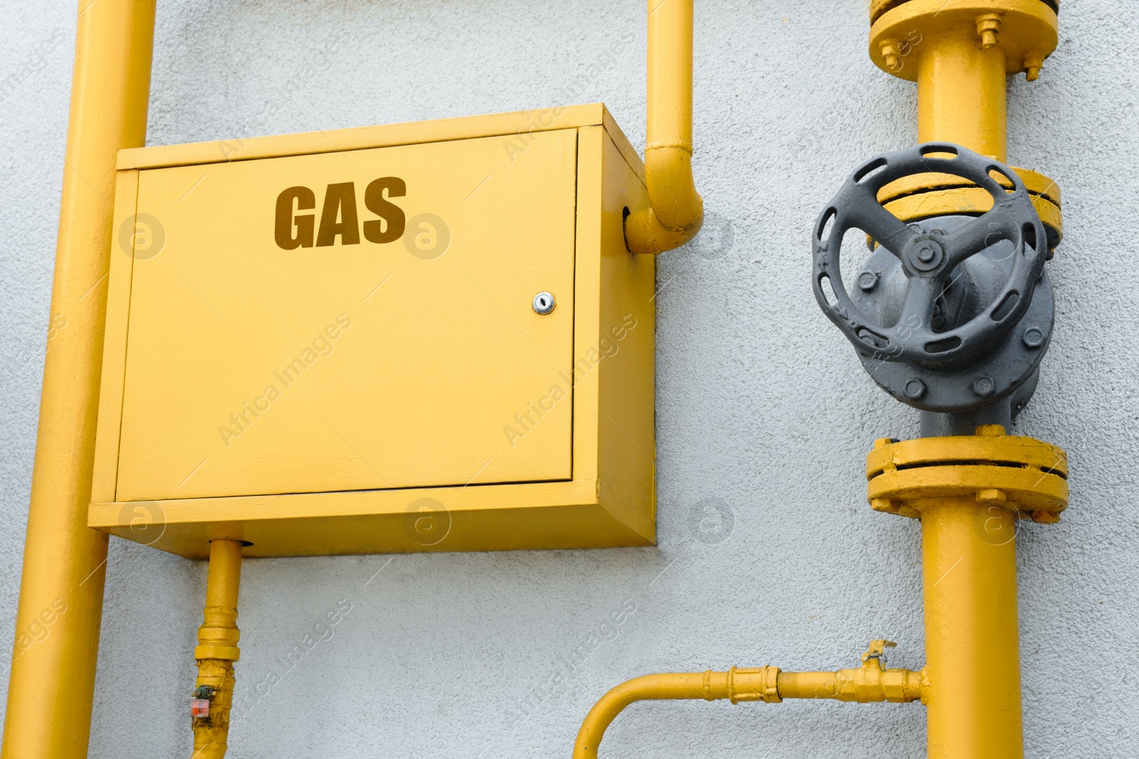 Photo of Gas meter box and pipes near grey wall outdoors