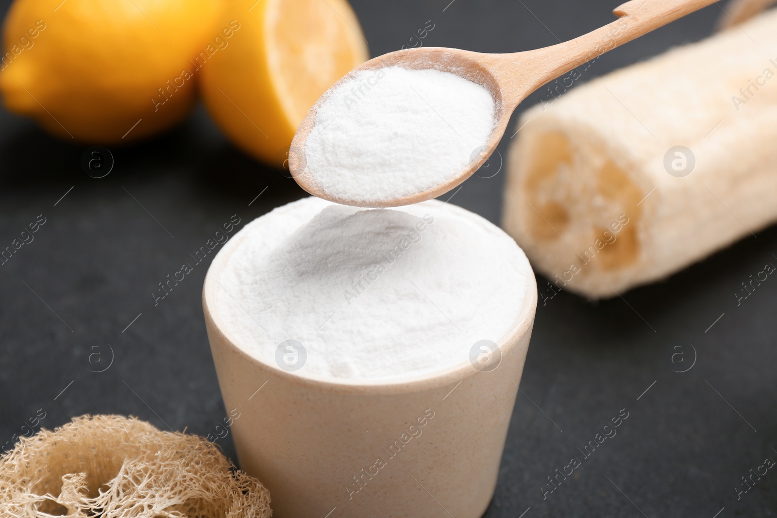 Photo of Spoon with baking soda over bowl on dark table