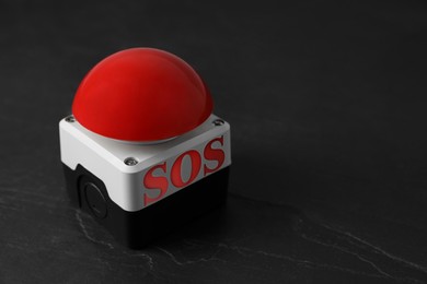 Image of Red SOS button on black table. Space for text