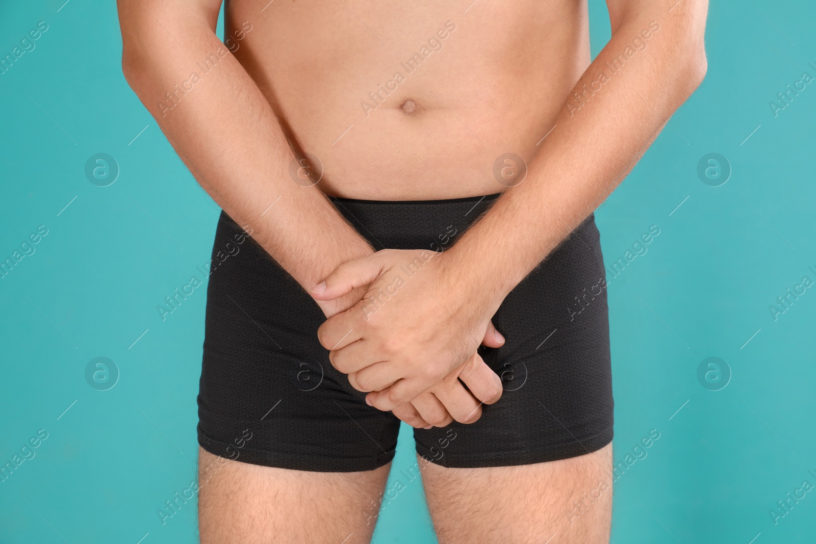 Photo of Man suffering from pain on turquoise background, closeup. Urology problems